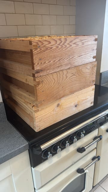 Three honey supers stacked in a kitchen, waiting to be extracted.